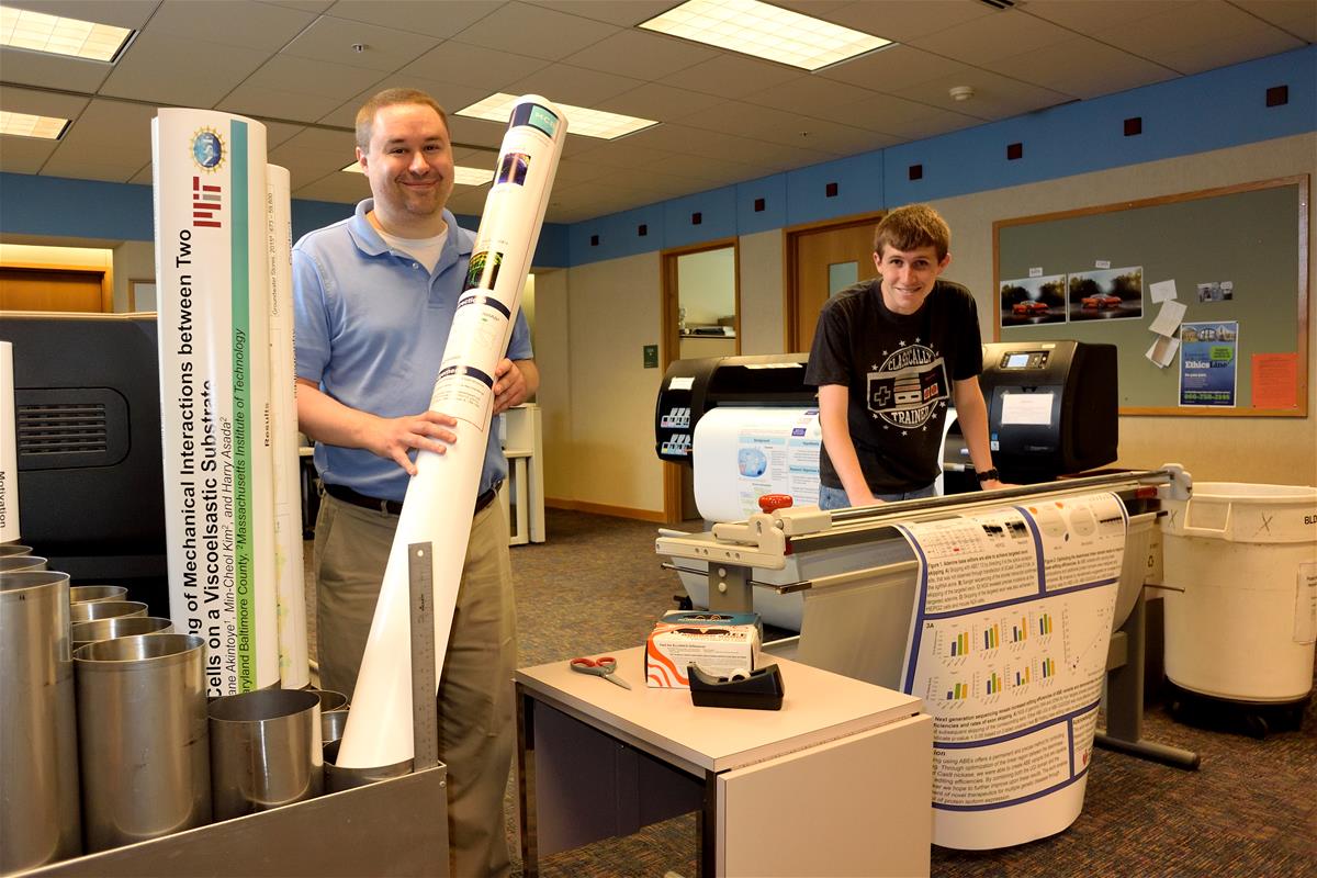 An Internet Technology Services employee helps a student print a poster