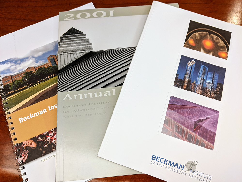 A photo of several annual reports spread out on a wood tabletop.