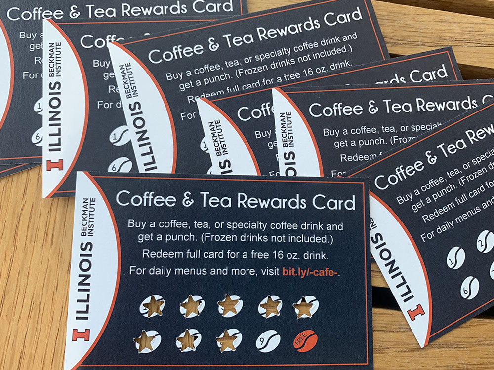 A group of reward punch cards for the Beckman Cafe spread on a wood table top.