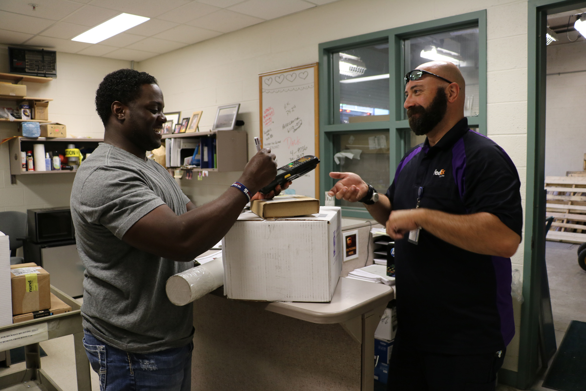 Beckman Shipping and Receiving employee signs for packages from a FedEx employee at the Beckman Institute.