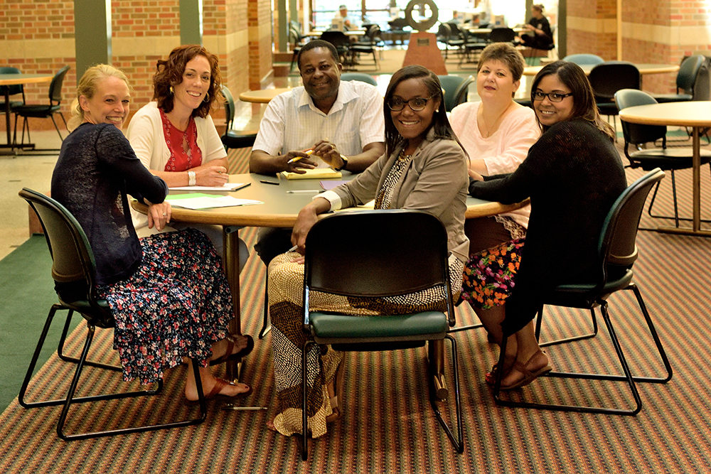 Members of the Beckman Institute Business Office pose in the atrium of the Beckman Institute at the University of Illinois.