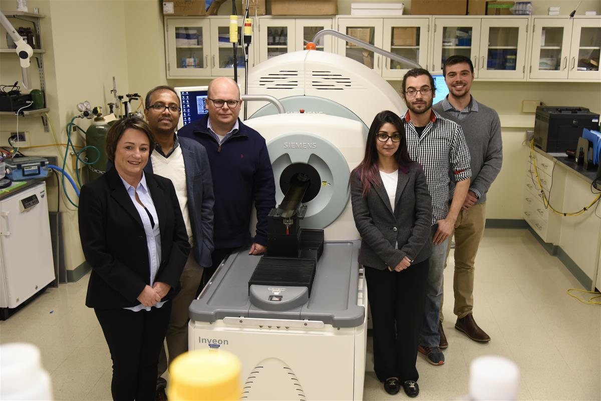 Collaborators pose in front of the Beckman Biomedical Imaging Center's microPET/SPECT/CT scanner.