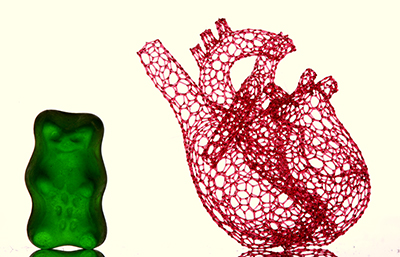 green gummy beat next to a 3D-printed lacy heart to show scale.